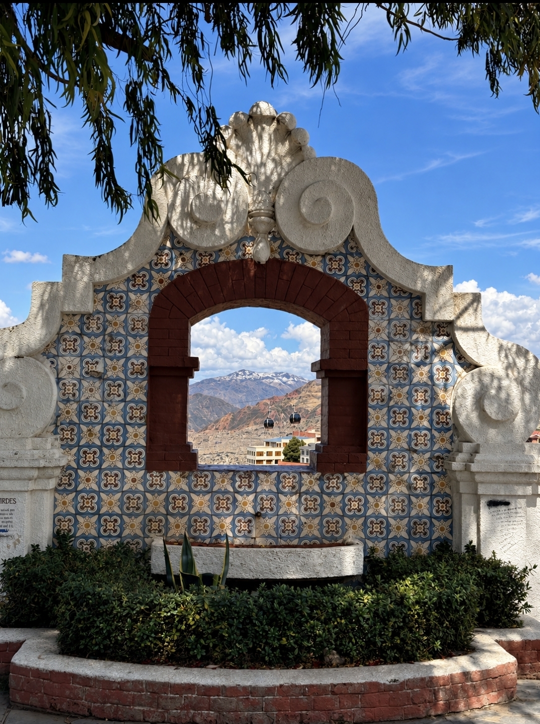 Cable cars and snow-capped mountains framed by the tiled arch at Mirador El Montículo in Sopocachi