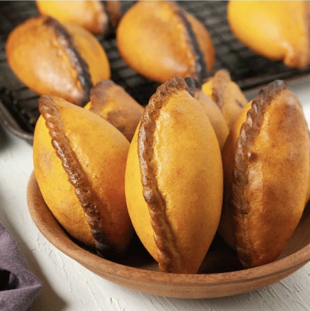 Golden baked salteñas served in a wooden bowl, a classic La Paz breakfast pastry