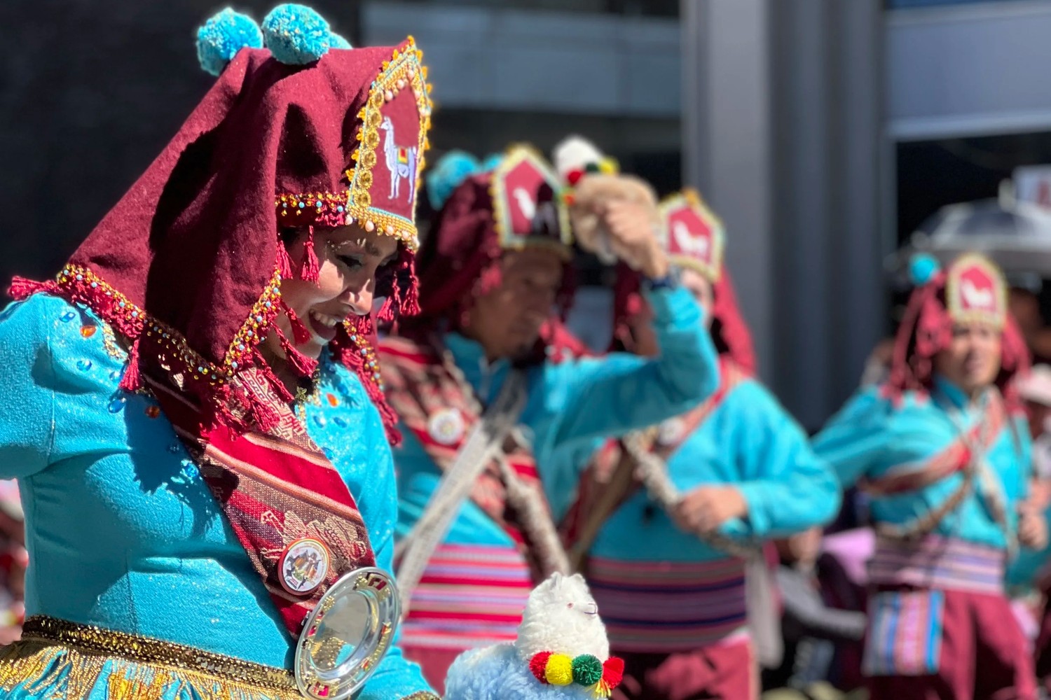 A Gran Poder dancer in a turquoise and burgundy costume with intricate beadwork