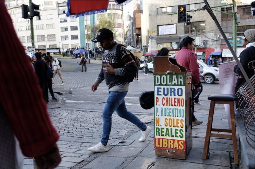 Street money changer in La Paz with a board showing exchange rates for dollars, euros and other currencies